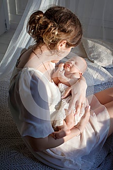 Happy family mother playing and hug with newborn baby in bed