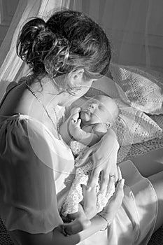 Happy family mother playing and hug with newborn baby in bed. Black and white