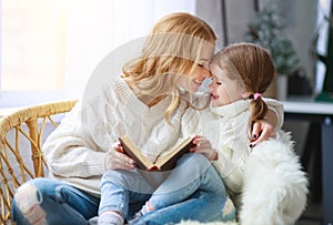 Happy family mother reads book to child to daughter by window