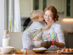 Happy family mother and son bake kneading dough in kitchen