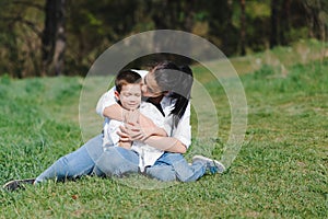 Happy family! Mother with son child playing having fun together on the grass in sunny summer day, life moment