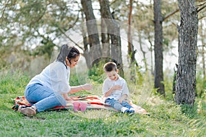 Happy family! Mother with son child playing having fun together on the grass in sunny summer day, life moment