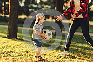 Happy family. Mother with son having fun playing football together on the grass on a sunny summer day