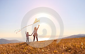 Happy family  mother and son  launch  kite on nature at sunset