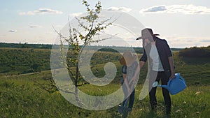 Happy family mother and son in the park plant a tree. Teamwork. A kid farmer helps a parent plant a tree. Happy family