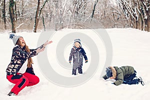 Happy family mother and sons having fun, playing with snow at winter walk outdoors. Happy christmas holidays. Winter snowy weather