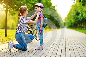 Happy family mother teaches child daughter to ride a bike in the Park