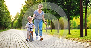 Happy family mother teaches child son to ride a bike in the Park