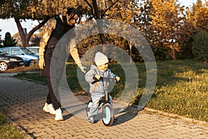 Happy family mother teaches child son to ride a bike in the Park. Crying boy fear, afraid idea. Family, childhood