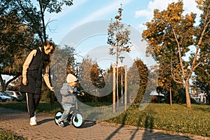Happy family mother teaches child son to ride a bike in the Park. Crying boy fear, afraid idea. Family, childhood