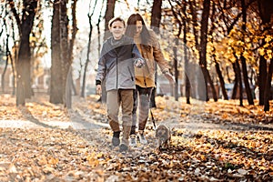 Happy family mother and teen boy son having fun with cocker spaniel puppy in autumn park