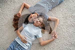 Happy family. Mother and teenage daughter lying resting on floor at home smiling at camera