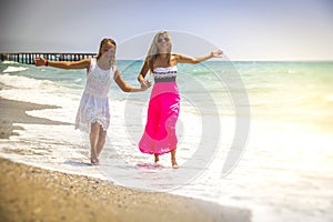 Happy family mother and teenager daughter run, laugh and play at beach