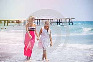 Happy family mother and teenager daughter walk, laugh and play at beach