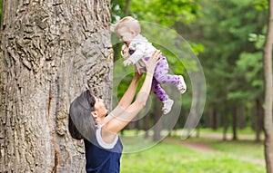 Happy family. Mother throws up baby, playing outdoors