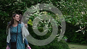 Happy family mother with two Daughters little siblings kids have fun sniffing flowers on trees enjoying summer holidays