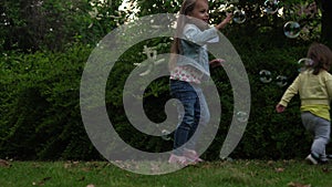 Happy family mother, two Three little siblings kids are blowing soap bubbles and enjoying summer holidays in garden or