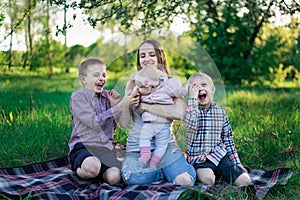 Happy family on nature. Playful sons with little sisters and mother outdoors. Large family