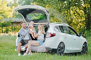 Happy family near car trunk on sunny day. Road trip