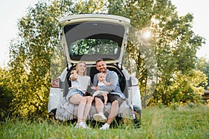 Happy family near car trunk on sunny day. Road trip