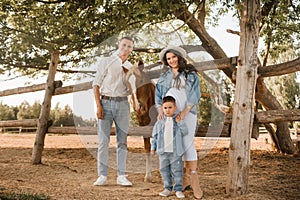 Happy family near horses at a farmer& x27;s ranch at sunset