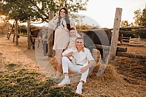 Happy family near horses at a farmer& x27;s ranch at sunset