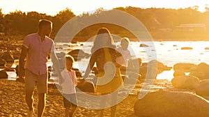 Happy family near the sea. Field and trees in countryside. Warm colors of sunset or sunrise. Loving parents and