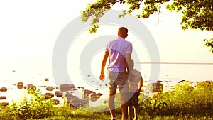 Happy family near the sea. Field and trees in countryside. Warm colors of sunset or sunrise. Loving parents and