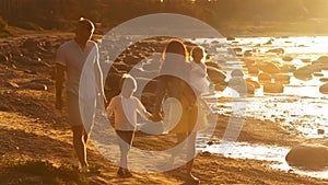 Happy family near the sea. Field and trees in countryside. Warm colors of sunset or sunrise. Loving parents and