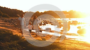 Happy family near the sea. Field and trees in countryside. Warm colors of sunset or sunrise. Loving parents and