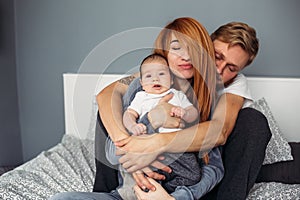 Happy family with newborn baby on the bed