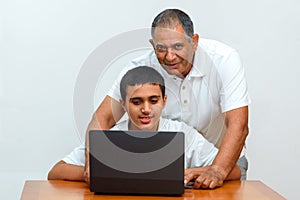 Happy family old grandfather and grandson on laptop.Elderly teacher trainer and teen pupil boy.