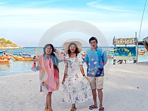 Happy family of old parents and adult daughter standing together at sea view sand beach