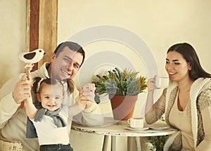 Happy family with one year old baby girl drinking coffee indoor