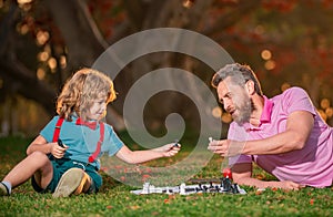Happy family outdoor. Father and son playing chess in autumn fall garden. Intelligent child, smart kids.