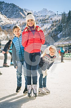 Happy family outdoor ice skating at rink. Winter activities