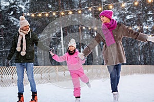 Happy family at outdoor skating rink in winter