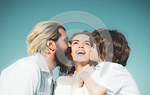 Happy family outdoors. Father and son embrace and kissing mother. Young smiling family with one child having fun