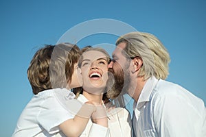 Happy family outdoors. Father and son embrace and kissing mother. Young smiling family with one child having fun