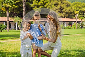 Happy family outdoors on the grass in a park, smiling faces, having fun