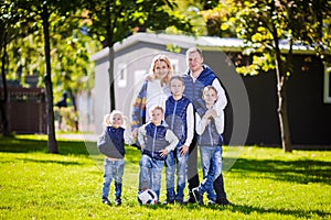 Happy Family Outdoors. Happy Caucasian family standing outside their house and hugging. Family with four children in front house.