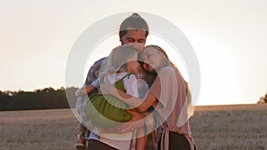 Happy family outdoors hugging together with love. Caucasian parents with child daughter hug embrace cuddle in sunlight