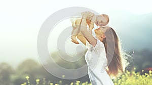 happy family outdoors. mother throws baby up, laughing and playing in summer on nature