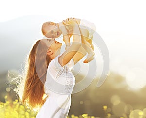 happy family outdoors. mother throws baby up, laughing and playing in summer on nature