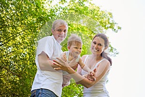 Happy family outdoors mum and dad hold baby boy kid