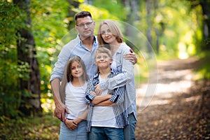 Happy family outdoors spending time together. Father, mother, daughter and son are having fun in a summer park at summer