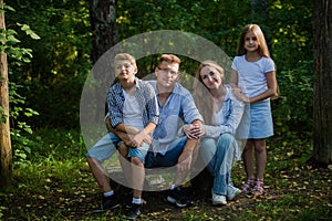 Happy family outdoors spending time together. Father, mother, daughter and son are having fun in a summer park at summer