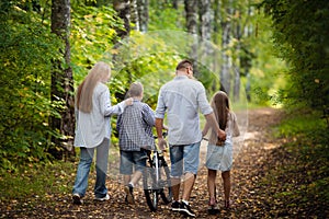 Happy family outdoors spending time together. Father, mother, daughter and son are having fun in a summer park at summer