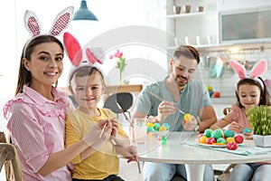 Happy family painting Easter eggs in kitchen