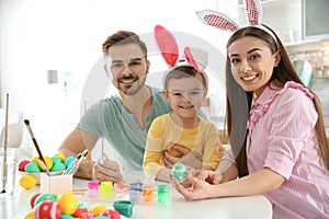 Happy family painting Easter eggs in kitchen